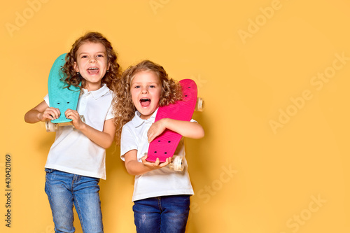 Two Active and happy girls with curly hair having fun with penny