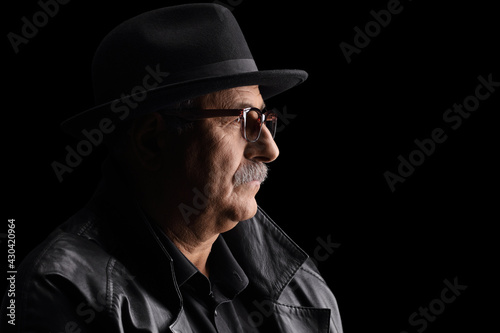 Close up profile shot of a mature man with a hat and leather coat