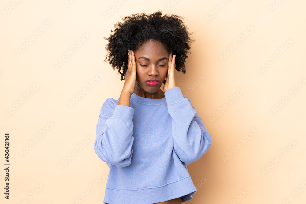 Young African American woman isolated on beige background with headache Young African American woman isolated on beige background with headache