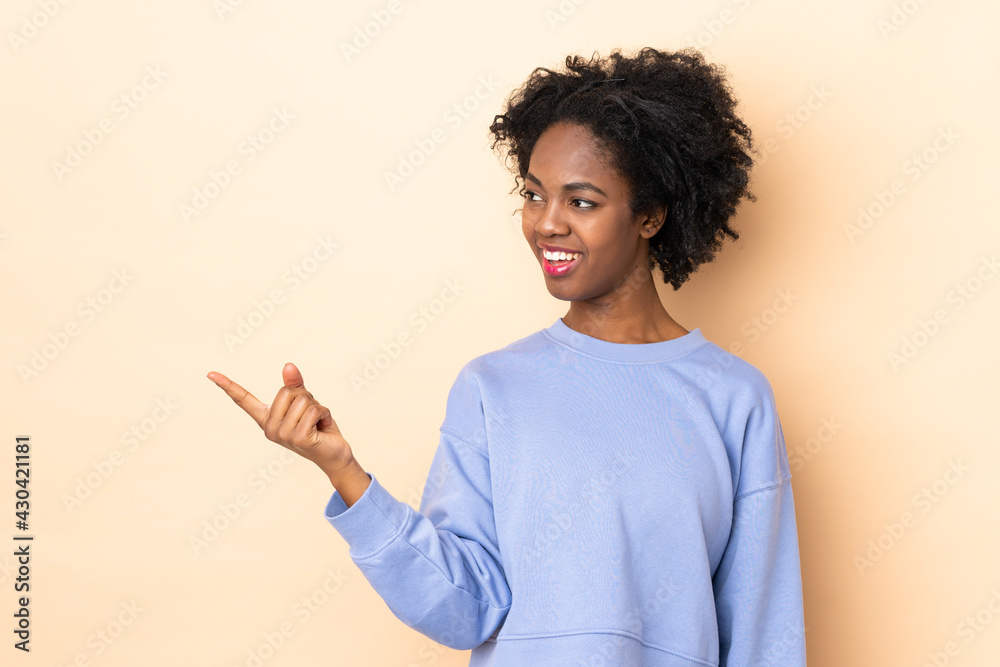 Young African American woman isolated on beige background intending to realizes the solution while lifting a finger up Young African American woman isolated on beige background intending to realizes the solution while lifting a finger up