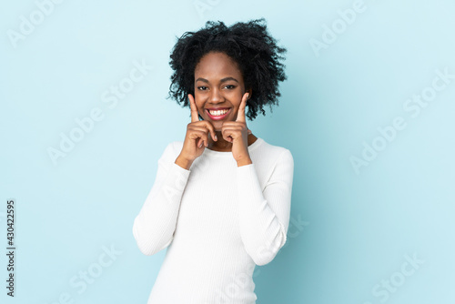 Young African American woman isolated on blue background smiling with a happy and pleasant expression