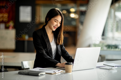 Portrait of Accounting businesswoman working on note laptop computer and analyzing real estate investment data, Financial and tax systems concept.