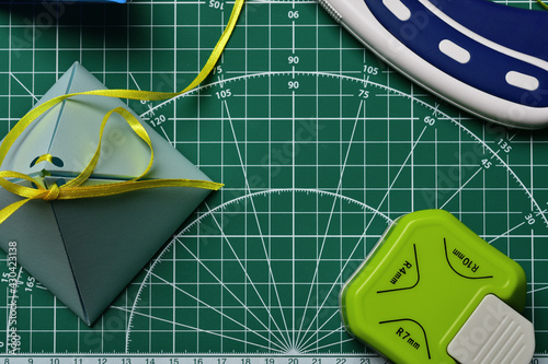 Homemade gift box on a green cutting mat with scrapbooking tools.