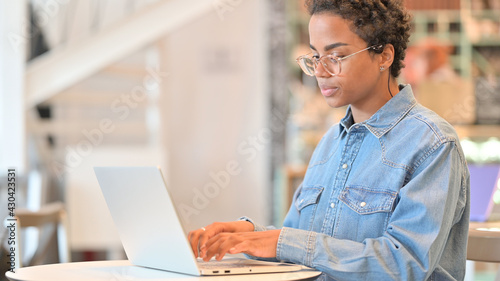 African Woman Working on Laptop at Cafe 