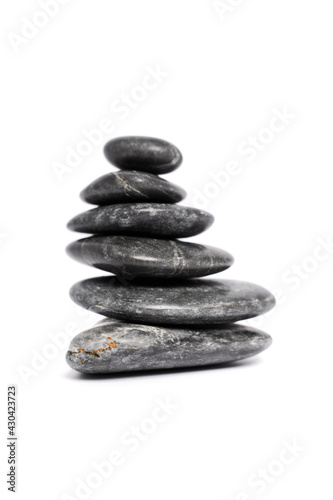 Zen stones or black pebbles stacked on top of each other like a pyramid, isolated on white background. Harmony, balance and meditation, spa, massage, relax concept. 