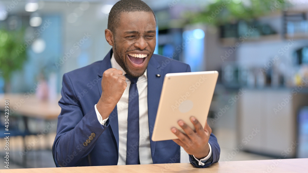 African Businessman Celebrating Success on Tablet in Office 