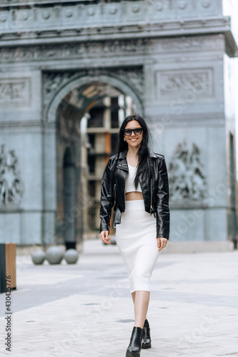 Young beautiful brunette in sunglasses and a fashionable outfit walking in the city