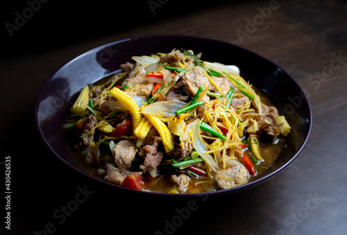 Stir fried pork and ginger with mixed vegetable in a black plate on wooden table
