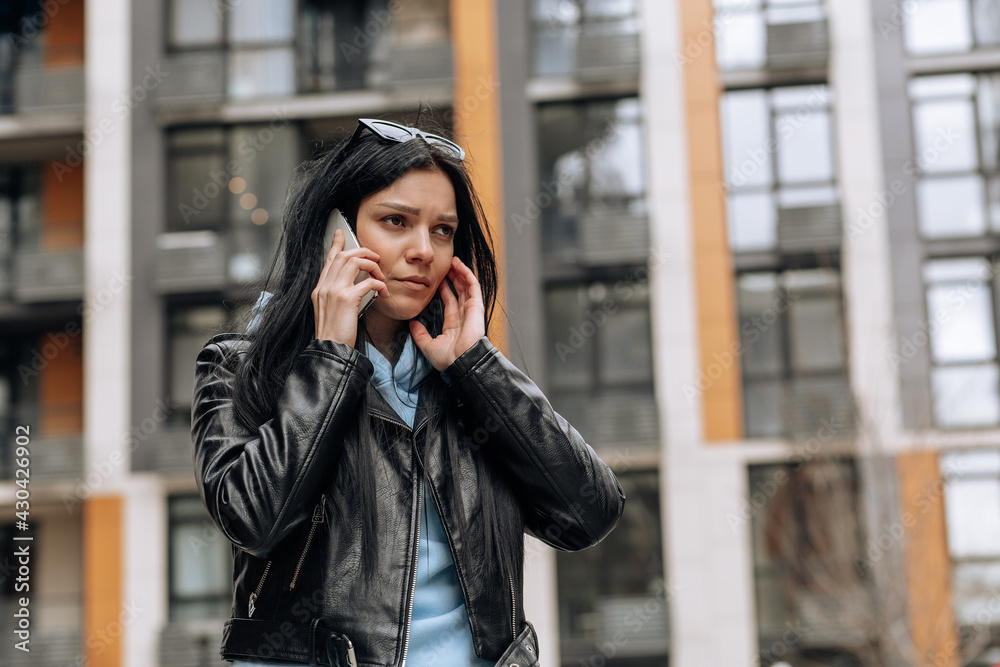 Young beautiful brunette girl on the street talking on the phone with a sad expression on her face Young beautiful brunette girl on the street talking on the phone with a sad expression on her face