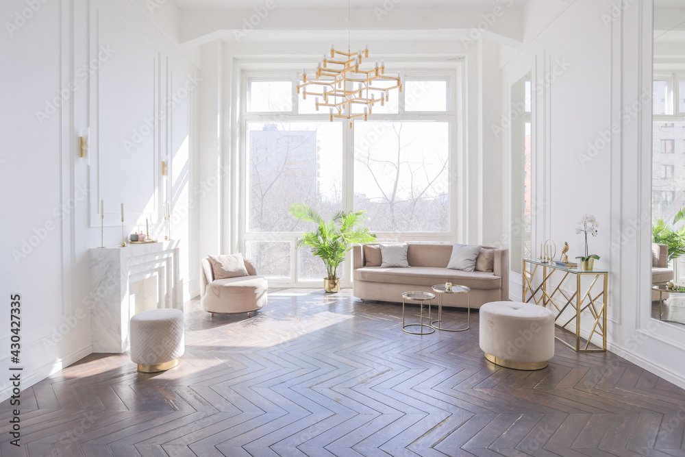very light and bright interior of luxurious cozy living room with chic soft beige furniture with gold metallic elements, huge window to the floor and wooden parquet - obrazy, fototapety, plakaty 
