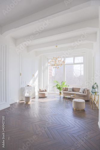 very light and bright interior of luxurious cozy living room with chic soft beige furniture with gold metallic elements, huge window to the floor and wooden parquet © 4595886