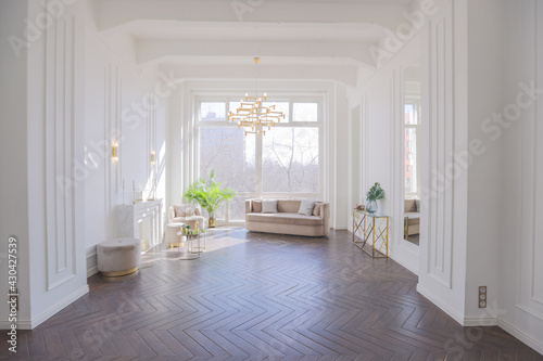Fototapeta Naklejka Na Ścianę i Meble -  very light and bright interior of luxurious cozy living room with chic soft beige furniture with gold metallic elements, huge window to the floor and wooden parquet
