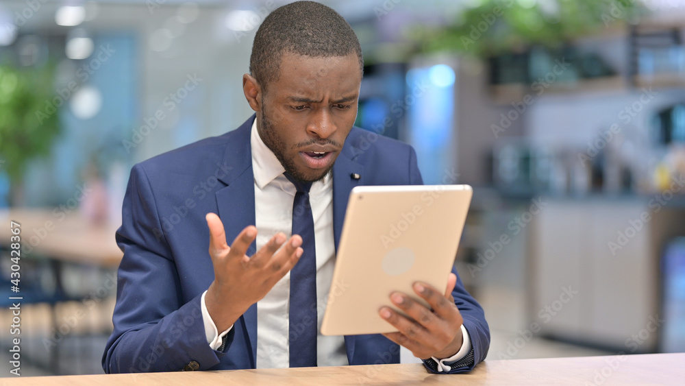 African Businessman Reacting to Loss on Tablet in Office 