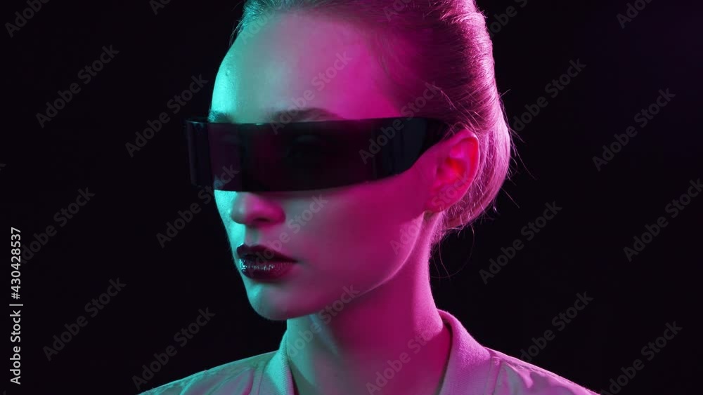 Portrait of teenage girl in cyberpunk style. Young woman posing in futuristic sunglasses. Creative studio light. Portrait of teenage girl in cyberpunk style. Young woman posing in futuristic sunglasses. Creative studio light.