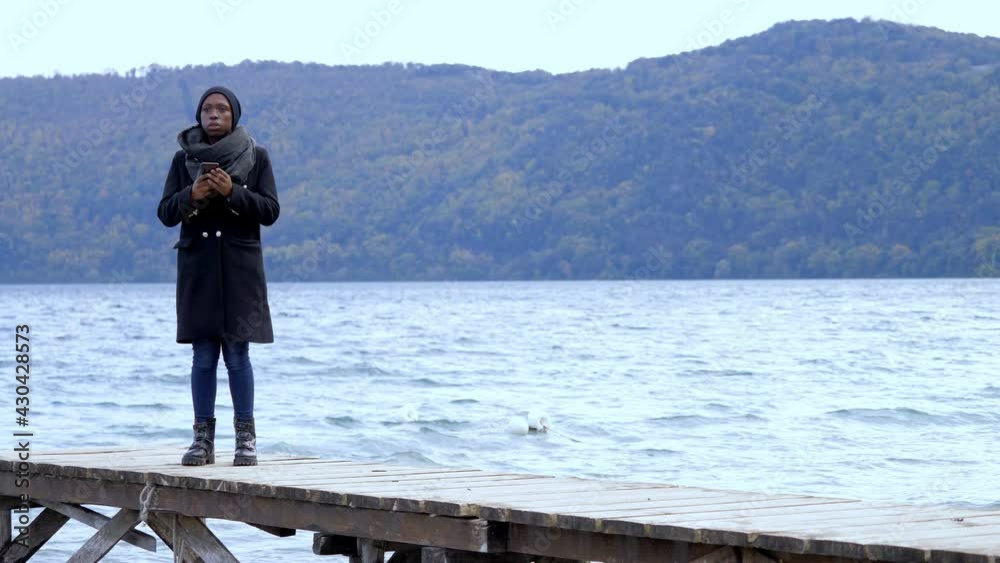 globalization, social - black woman by the lake checks her smartphone globalization, social - black woman by the lake checks her smartphone