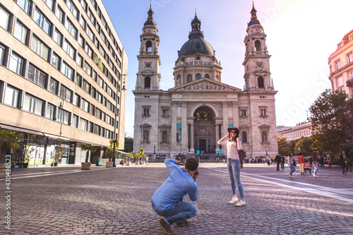 Young couple take pictures of each other while standing in front of St. Stephens Basilica in Budapest. photo