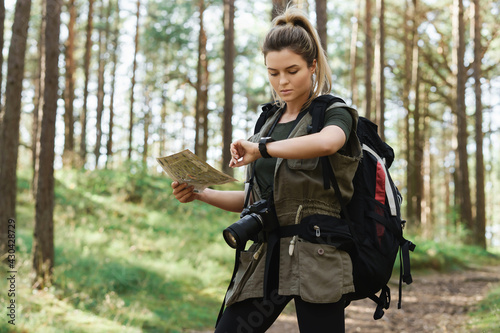 Obraz na plátně Female hiker with big backpack using map for orienteering in the forest