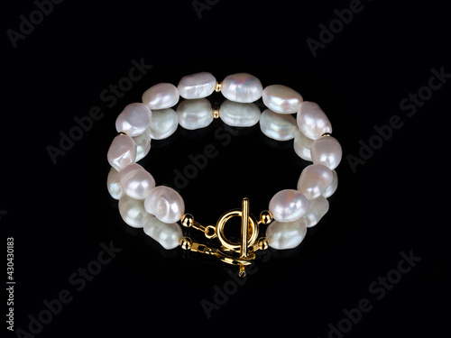 Luxury elegant baroque pearl golden bracelet on black mirror background