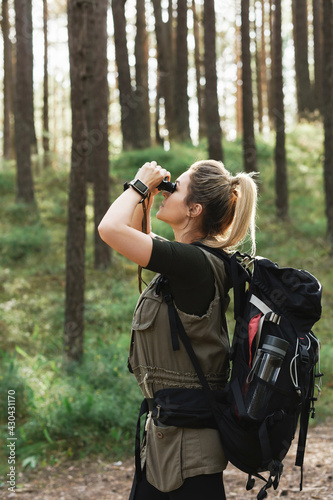 Female hiker is using binoculars for bird watching in green forest © blackday