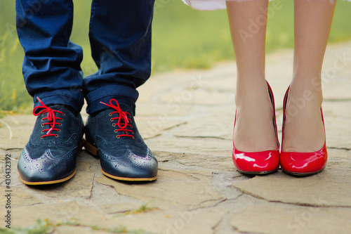 Bride and groom in beautiful shoes standing on the sidewalk in the park