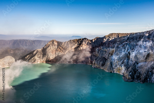 Ijen volcano crater with lake and sulphur mining. Beautiful Landscape mountain and green lake with smoke sulfur in the morning in a Kawah Ijen volcano. Beautiful landmark from East Java  Indonesia