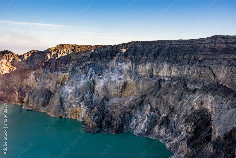 Fototapeta premium Ijen volcano crater with lake and sulphur mining. Beautiful Landscape mountain and green lake with smoke sulfur in the morning in a Kawah Ijen volcano. Beautiful landmark from East Java, Indonesia