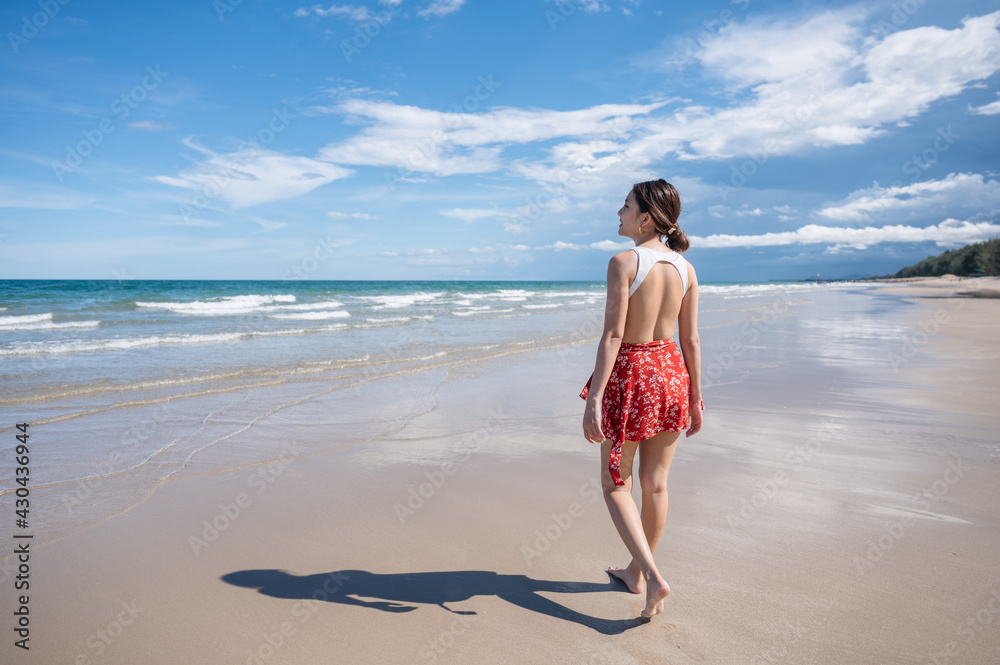 Attractive young asian woman in swimwear walking on the beach at tropical sea in sunny day Attractive young asian woman in swimwear walking on the beach at tropical sea in sunny day