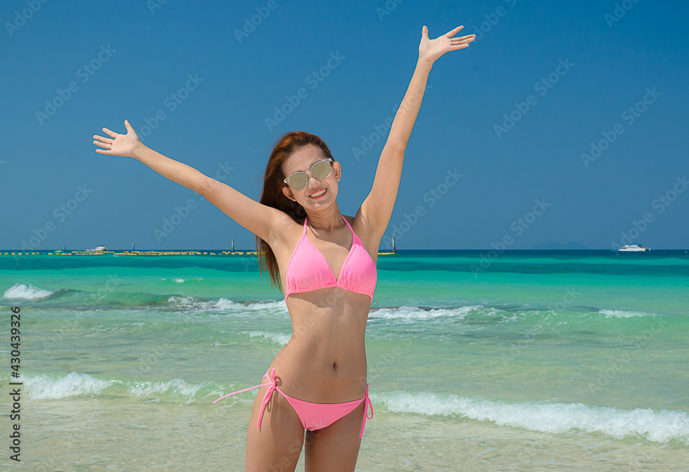beautiful Asian woman happily wears a pink bikini and wears sunglasses on the beach. beautiful Asian woman happily wears a pink bikini and wears sunglasses on the beach.