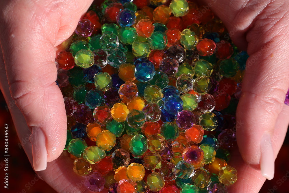 Small colorful plastic balls in the hands - obrazy, fototapety, plakaty 
