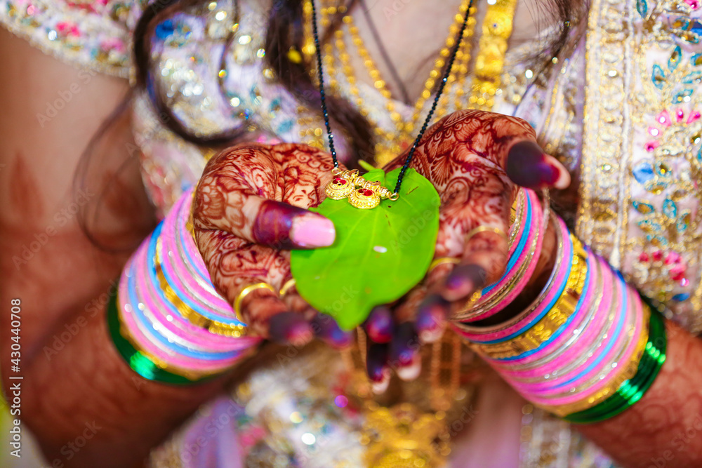 Indian Groom and bridal holding mangalsutra or gold necklace with green  leaf in hand Stock Photo | Adobe Stock