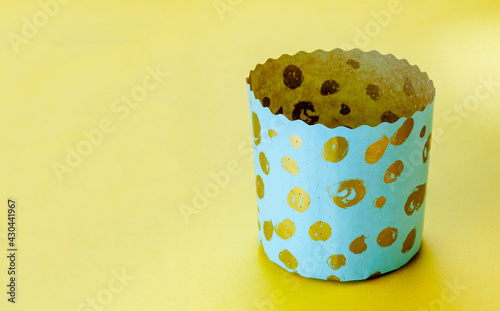Easter cake. Paper baking pans. Panettone paper baking form isolated over yellow background. Traditional decoration paper baking pans for easter cake