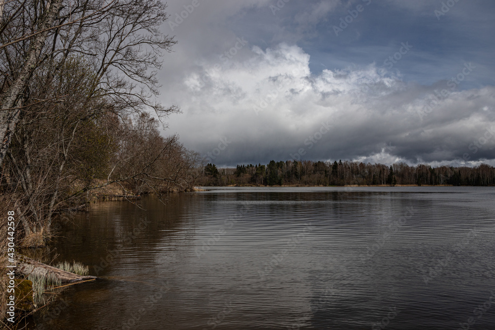 beautiful big lake found in Latvian forests with cloudy dramatic sky reflected in calm clean spring water beautiful big lake found in Latvian forests with cloudy dramatic sky reflected in calm clean spring water