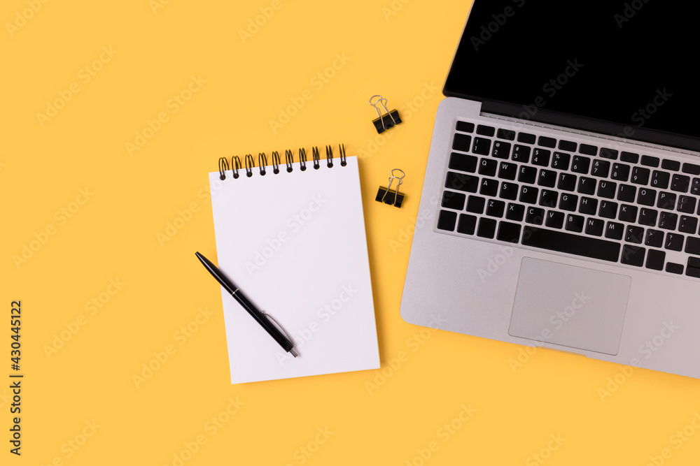 Workspace for e-learning with laptop and open notepad on a yellow background. Homeschooling concept with copy space. Workspace for e-learning with laptop and open notepad on a yellow background. Homeschooling concept with copy space.