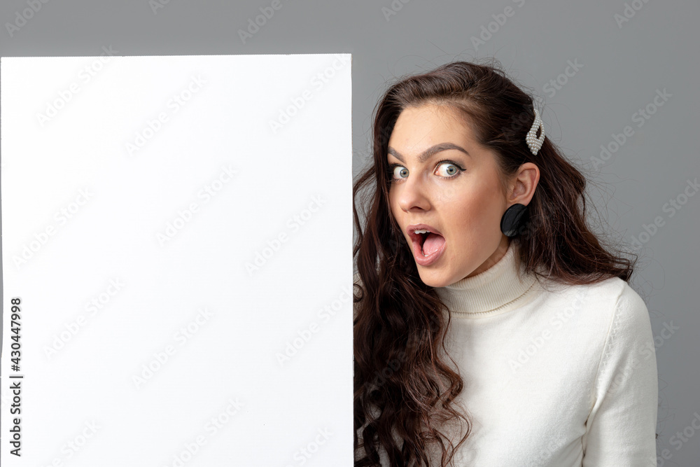 beautiful sensual woman with long curly hair shows a blank banner, isolated on gray, copy space beautiful sensual woman with long curly hair shows a blank banner, isolated on gray, copy space