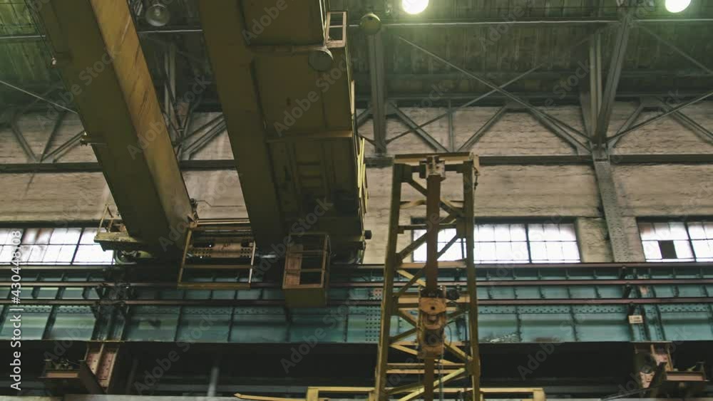 Low-angle shot of huge crane excavator for lifting heavy loads moving along assembly shop at tractor plant Low-angle shot of huge crane excavator for lifting heavy loads moving along assembly shop at tractor plant