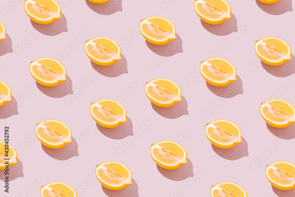 Lemon halves pattern on a pale pink background. Sunny yellow summer fruit and shadow. Retro beach food aesthetic concept.