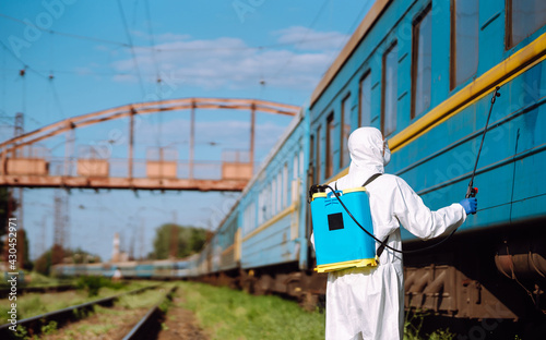Man wearing protective suit disinfecting public a train with spray chemicals to preventing the spread of coronavirus, pandemic in quarantine city. Covid -19. Cleaning concept.
