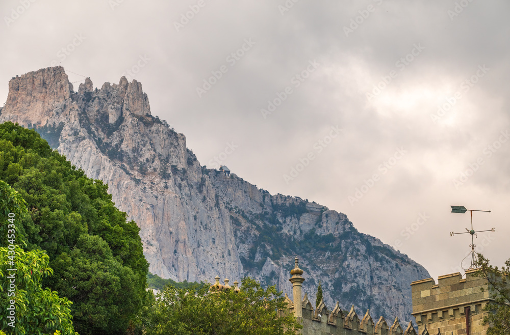 The walls and towers of the old palace on the background of high mountains and cloudy sky