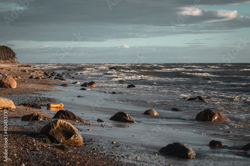 Fototapeta Naklejka Na Ścianę i Meble -  Sandy sea coast with some roks in water. Sunset seascape view of baltic sea in Lithuania near Klaipeda.