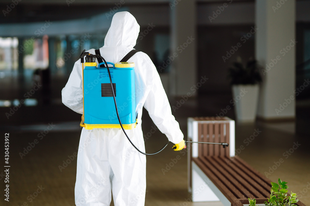 Disinfecting of office to prevent COVID-19, Man in protective hazmat suit with with spray chemicals to preventing the spread of coronavirus, pandemic in quarantine city.
