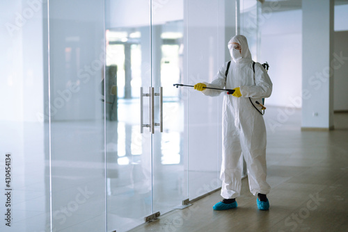 Disinfecting of office to prevent COVID-19, Man in protective hazmat suit with with spray chemicals to preventing the spread of coronavirus, pandemic in quarantine city.  © maxbelchenko