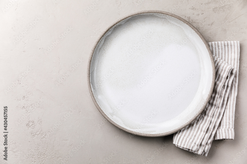 Table setting with empty white plate and striped linen napkin on grey concrete background template Table setting with empty white plate and striped linen napkin on grey concrete background template