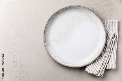 Table setting with empty white plate and striped linen napkin on grey concrete background template