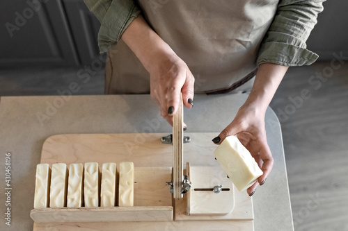 A woman makes handmade natural soap.The finished soap is cut into pieces using special machine. Home spa. Small business