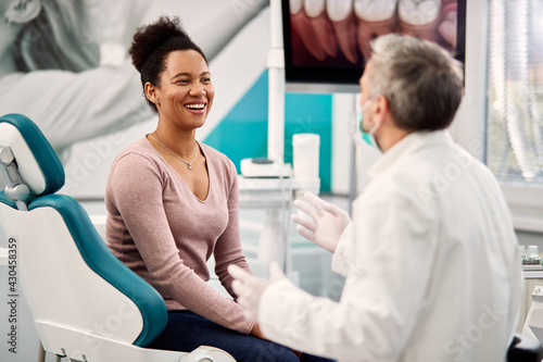 Happy Black woman talking to her dentist during appointment at dental clinic. photo