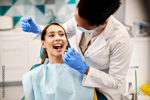 Young beautiful woman having her teeth examined during dental appointment at dentist's office.