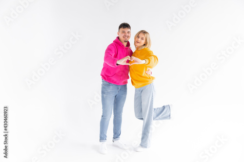 Romantic joyful couple smiling and showing heart gesture together isolated over white background © ALEXSTUDIO