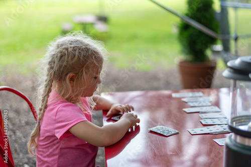 Little girl playing solitaire at an outdoor table photo
