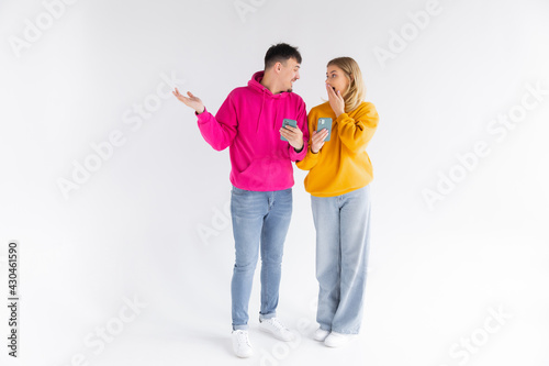 Photo of happy people man and woman laughing while pointing finger at smartphone isolated over white background