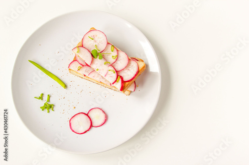 Toasted toast with fresh chopped radishes and green herb on the white plate. Healthy breakfast. Sandwich with vegetable.